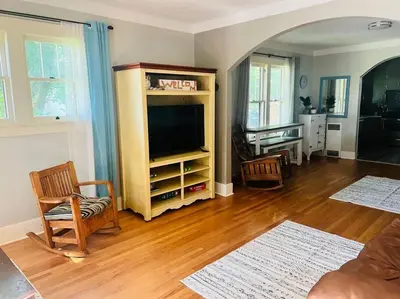 a living room with a flat screen tv and wooden floors at Walk to Dining Breweries and Shops Plus New Hot Tub in Louisville