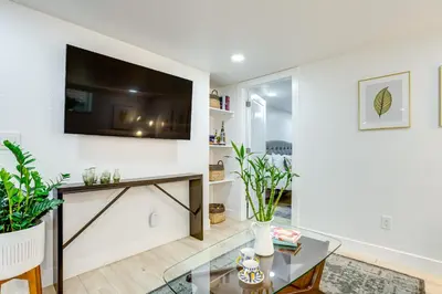 a living room with a flat screen tv on a wall at Steps from Wash Park Modern Apt, Patio and Parking in Denver