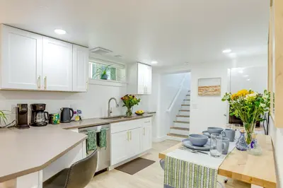 a kitchen with white cabinets and a table with chairs at Steps from Wash Park Modern Apt, Patio and Parking in Denver