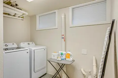 a laundry room with a washing machine and a table at Steps from Wash Park Modern Apt, Patio and Parking in Denver