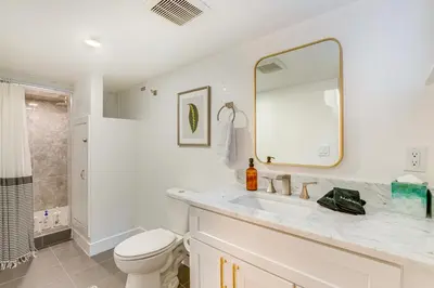 a bathroom with a sink and a toilet and a mirror at Steps from Wash Park Modern Apt, Patio and Parking in Denver