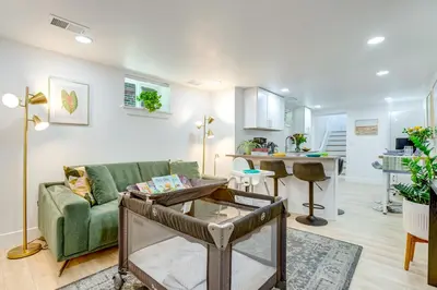 a living room with a green couch and a kitchen at Steps from Wash Park Modern Apt, Patio and Parking in Denver
