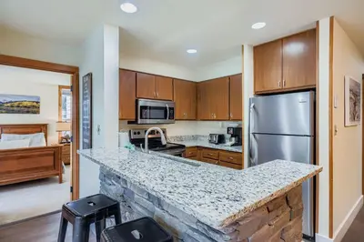 a kitchen with a granite counter top and a refrigerator at 1483 Lakeside condo in Keystone