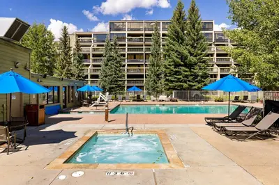 a pool with chairs and umbrellas next to a building at 1483 Lakeside condo in Keystone