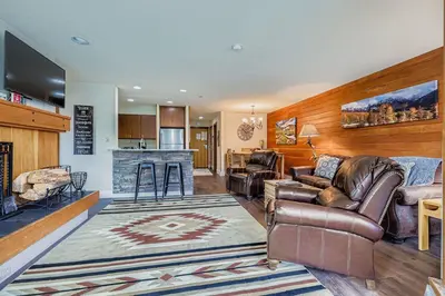 a living room with leather furniture and a kitchen at 1483 Lakeside condo in Keystone