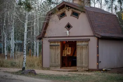 a small house with a garage in the woods at Mountain cabin w game room & hot tub in Bailey