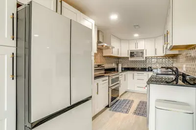 a kitchen with white cabinets and a refrigerator at Family-Friendly Aurora Apt with Shared Patio! in Aurora