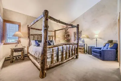 a bedroom with a wooden bed and a blue chair at Ski Run 307 - Mountain House Keystone in Keystone