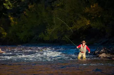 a man standing in a river holding a fishing rod at Ski Run 307 - Mountain House Keystone in Keystone