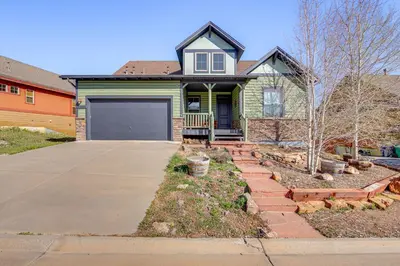 a green house with a garage and a driveway at Mtn Views and Private Hot Tub Granby Group Getaway! in Granby