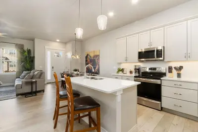 a kitchen with white cabinets and a kitchen island with chairs at NOCO Retreat with King Beds, Fireplace, Scenic Trails in Loveland