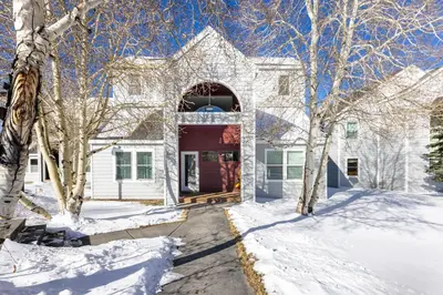 a white house with a red door in the snow at Meadow Cove B1 condo in Dillon