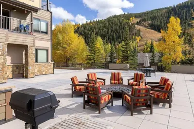 a patio with a grill and chairs and a table at 2756 Slopeside condo in Keystone
