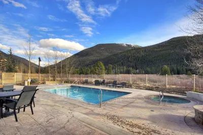 a swimming pool with a table and chairs and mountains at 2301 Red Hawk Lodge condo in Snake River Health Services Incorporated Heliport