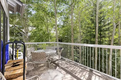a balcony with a table and chairs and trees at 2708 Chateaux DMont condo in Keystone