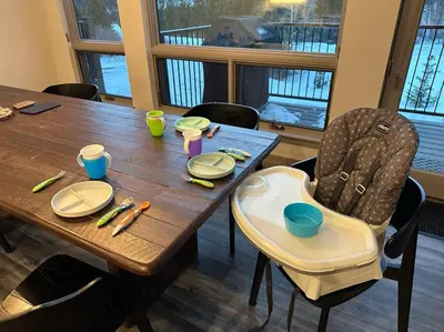 a wooden table with a childs high chair around it at Keystone Adventures Basecamp townhouse in Keystone