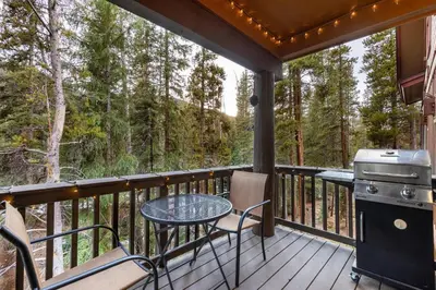 a deck with a table and chairs and a grill at 8766 Trappers Crossing townhouse in Keystone