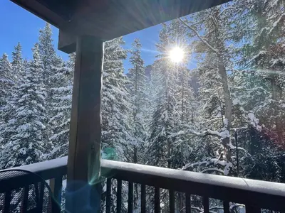 a winter view from a porch with snow covered trees at 8766 Trappers Crossing townhouse in Keystone