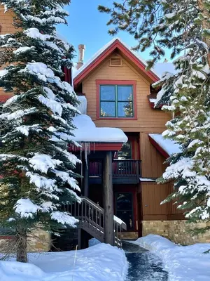 a house covered in snow with trees in front of it at 8766 Trappers Crossing townhouse in Keystone