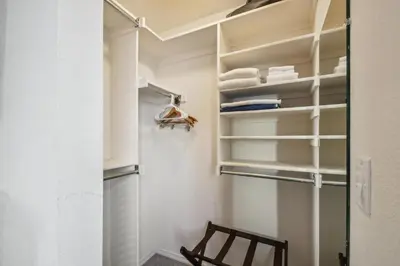 a walk in closet with white shelves and a wooden chair at Code & Comfort | Boston Commons in Englewood