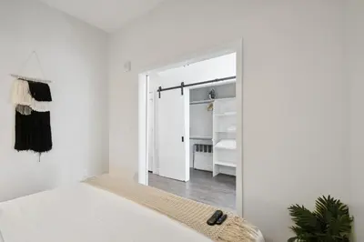 a white bedroom with a door leading to a closet at Urban Elegance | Espadin LoHi in Denver