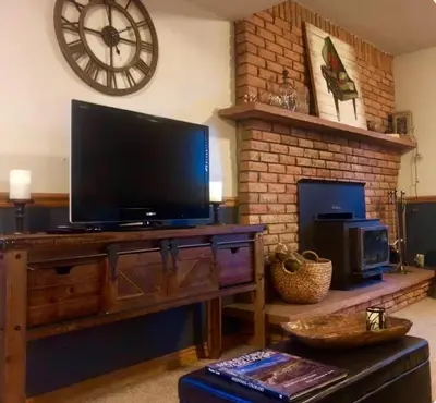 a living room with a large television on a wooden entertainment center at Cozy Garden Level Apartment Studio by Lake Loveland in Loveland