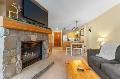 a living room with a stone fireplace with a flat screen tv at Buffalo Lodge 8386 in Keystone