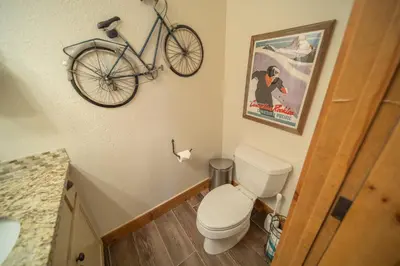 a bathroom with a toilet and a bike hanging on the wall at Settlers Creek 6536 by SummitCove Lodging in Keystone