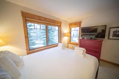 a bedroom with a white bed and two windows at Settlers Creek 6536 by SummitCove Lodging in Keystone