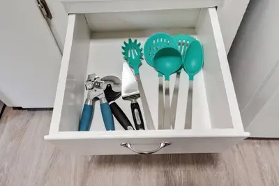 a white drawer filled with spatulas and spoons at 94 WalkScore King Bed Capitol Hill Beachy Apt in Denver