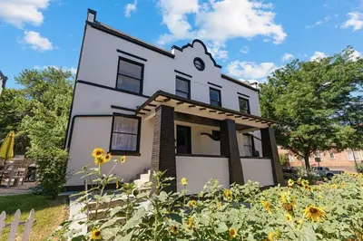 a white house with sunflowers in front of it at 94 WalkScore King Bed Capitol Hill Beachy Apt in Denver