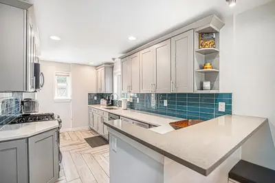 a kitchen with white cabinets and blue tile at Backyard Wonderland Ultimate Outdoor Fun in Denver