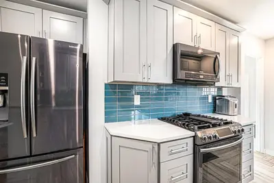 a kitchen with white cabinets and a stainless steel refrigerator at Backyard Wonderland Ultimate Outdoor Fun in Denver