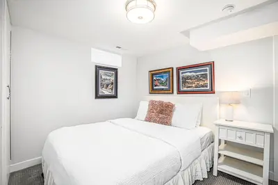 a white bedroom with a bed and a night stand at Backyard Wonderland Ultimate Outdoor Fun in Denver