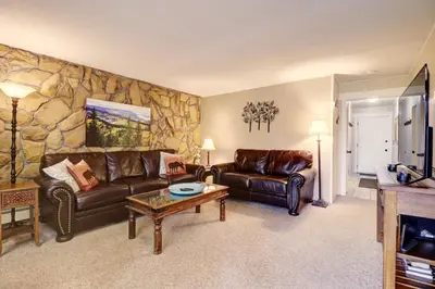 a living room with leather couches and a stone wall at A105 Lake Cliffe condo in Dillon