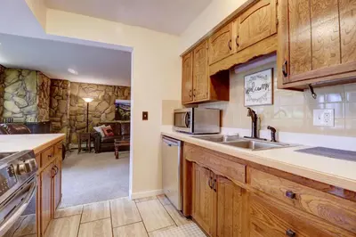 a kitchen with wooden cabinets and a sink and a living room at A105 Lake Cliffe condo in Dillon