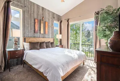 a bedroom with a bed and a large window at Fraser retreat w balcony , fireplace & BBQ in Fraser