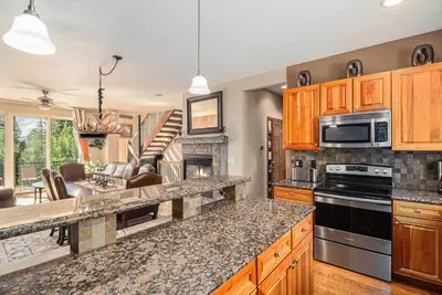 a kitchen with wooden cabinets and a stove top oven at Fraser retreat w balcony , fireplace & BBQ in Fraser