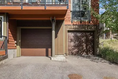a garage door of a building with a balcony at Fraser retreat w balcony , fireplace & BBQ in Fraser