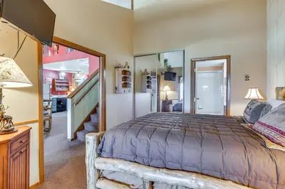 a bedroom with a large bed and a staircase at Walk to Ski Lift and Hiking Granby Ranch Condo! in Granby