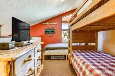 aury estate bedroom with a bunk bed and a television at Walk to Ski Lift and Hiking Granby Ranch Condo! in Granby