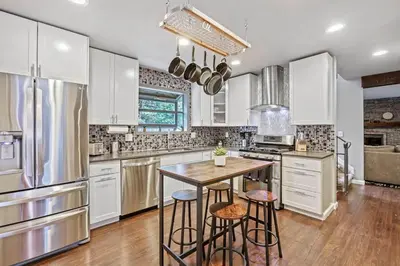 a kitchen with white cabinets and a table and stools at Modern Family Haven Fenced Yrd GrillFirepit in Westminster