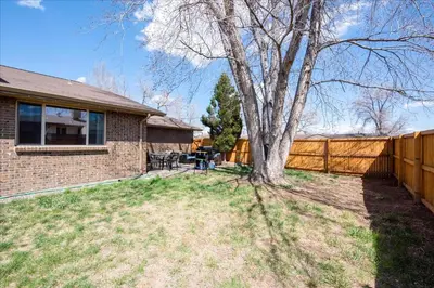 a house with a fence and a tree in the yard at Modern Chic Retreat Near Mtns & Red Rocks Wifi in Wheat Ridge