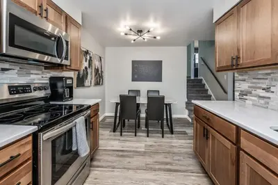 a kitchen with wooden cabinets and a table with chairs at Colorado home near Red Rocks w fenced yard in Wheat Ridge