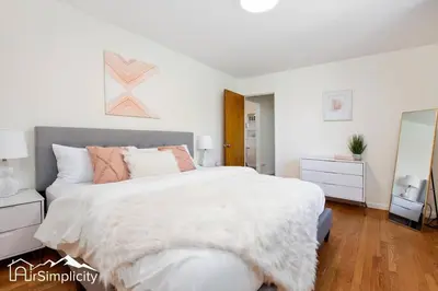 a white bedroom with a large bed and a mirror at Peaceful home w fire pit & game room in Denver