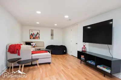 a living room with a couch and a flat screen tv at Peaceful home w fire pit & game room in Denver