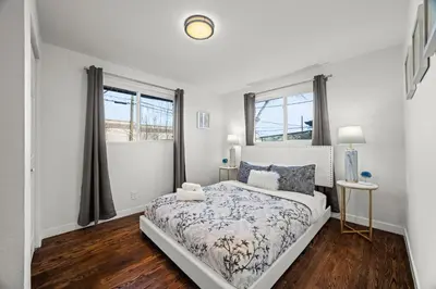 a white bedroom with a bed and two windows at The Denver Den Game Room Foosball in Westminster