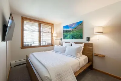 a bedroom with a bed with white sheets and a window at Premium Unit 2308 - 1Br - Zephyr Mountain Lodge condo in Winter Park
