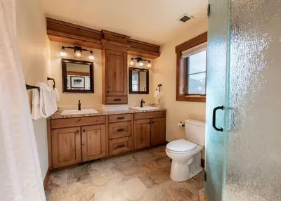 a bathroom with a toilet and two sinks and a mirror at Premium Unit 2801 - Zephyr Mountain Lodge condo in Winter Park