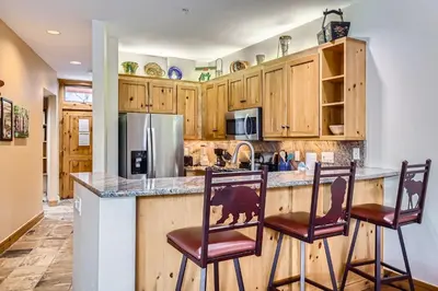 a kitchen with wooden cabinets and a counter with chairs at 8712 Ski Tip Townhomes townhouse in Keystone